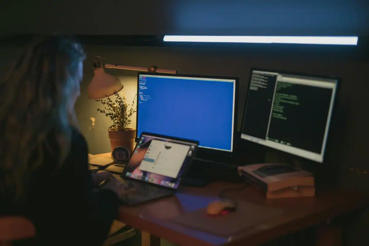 Woman developing code on monitors
