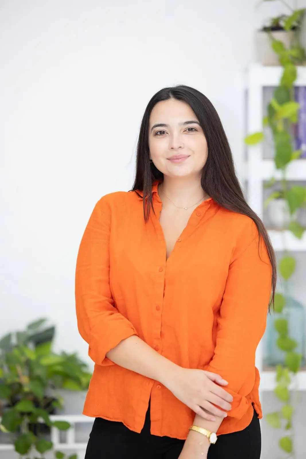 Woman in orange shirt smiling indoors