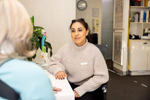 Woman in sweater consulting with another person