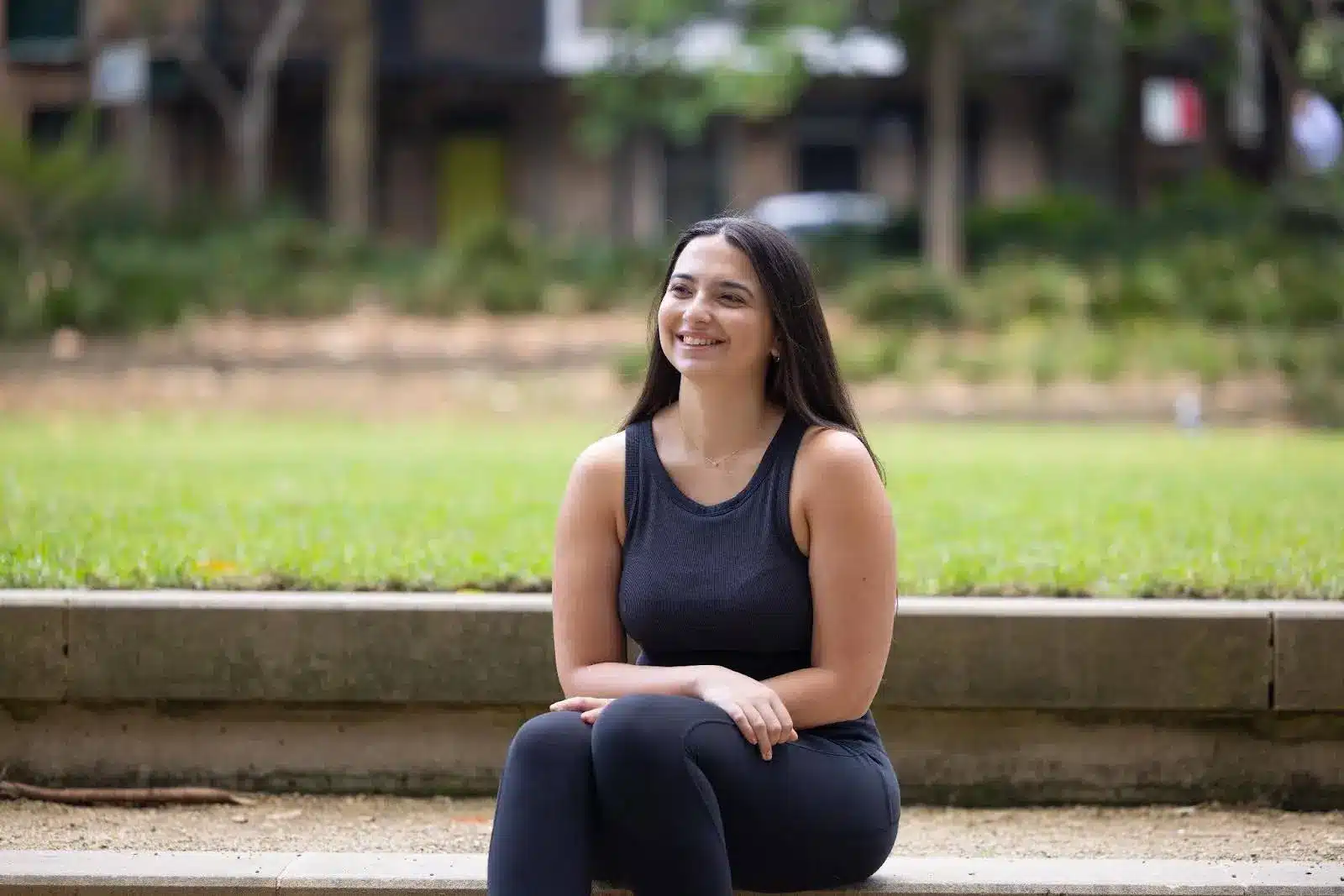 Woman sitting outdoors, smiling.